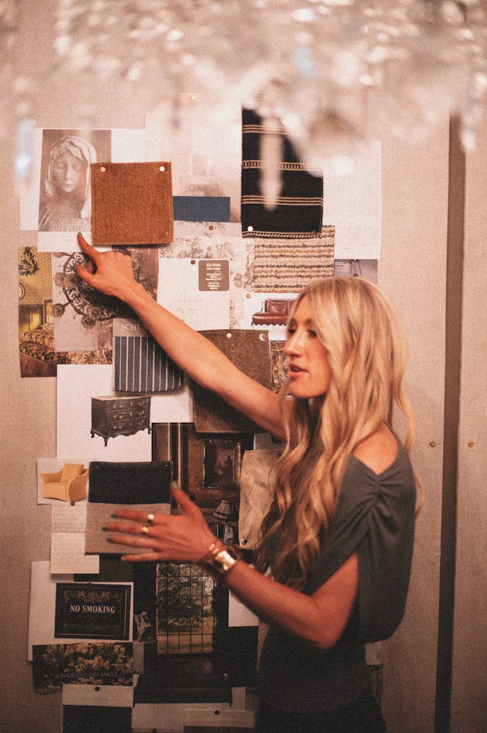 Woman organizing design samples on board in a cozy studio setting.